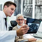 Cosmetic dentist reviewing dental X-ray with smiling patient