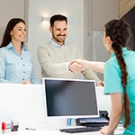 Man smiling while shaking hands with dental receptionist