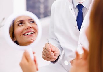 Woman smiling in reflection of handheld mirror