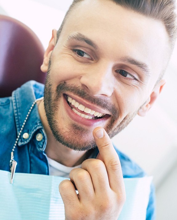 Man smiling at reflection in handheld mirror