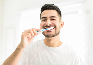 Man smiling while brushing teeth