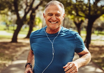 Senior man smiling while jogging outside