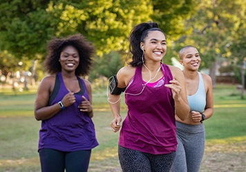 Group of women smiling while jogging in park