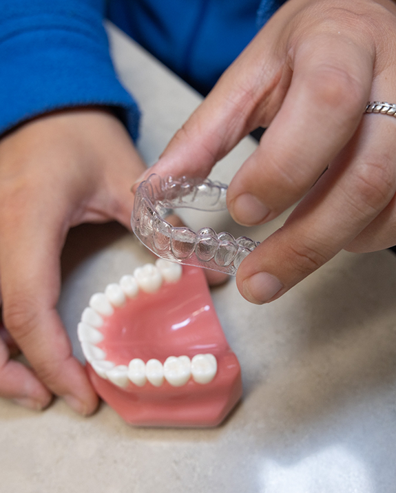 Dentist placing a clear aligner over a model of a row of teeth