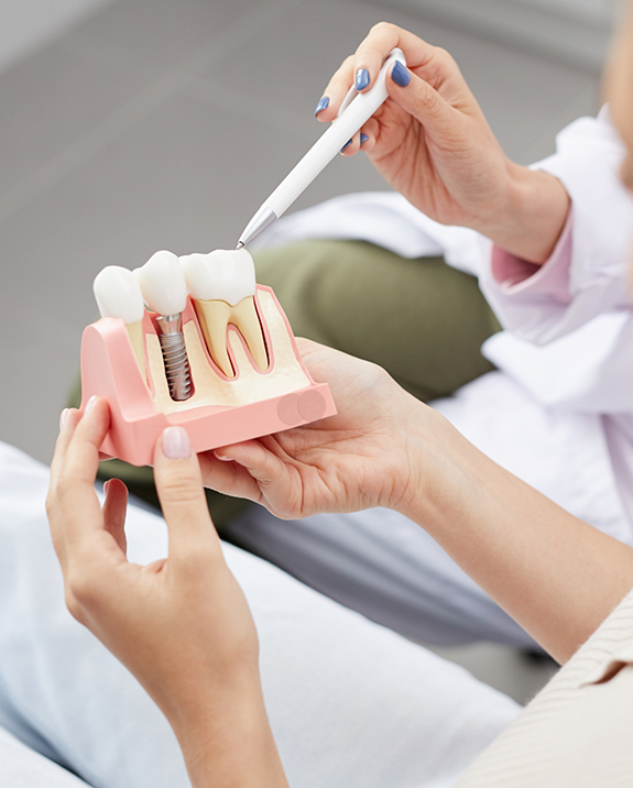 Dentist showing a patient a model of dental implants in Ellington