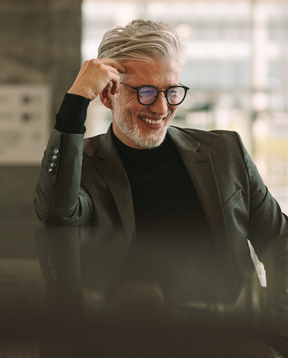 Smiling man with gray hair and glasses sitting at a table