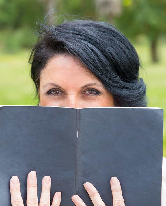 Woman covering her smile with a small black book
