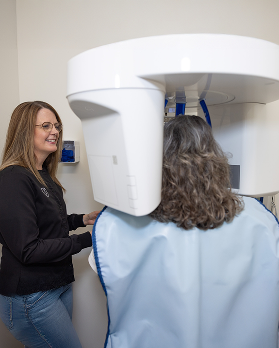 Dental team member taking a cone beam scan of a patients mouth and jaws