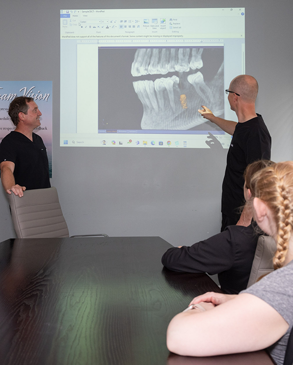 Doctor Jonathan and Doctor Shawn giving a presentation showing an x ray of a patient with a dental implant