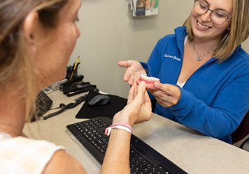 Dental team member showing a denture to a patient