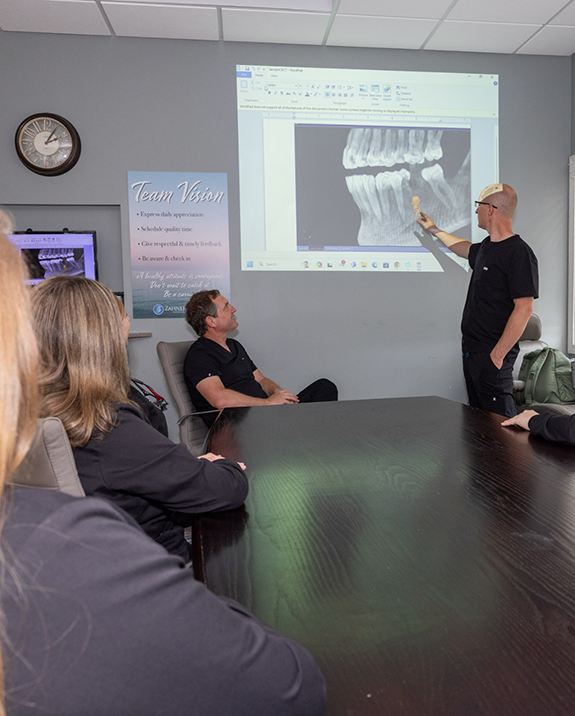 Dentist giving a presentation and showing an x ray of a person with a dental implant