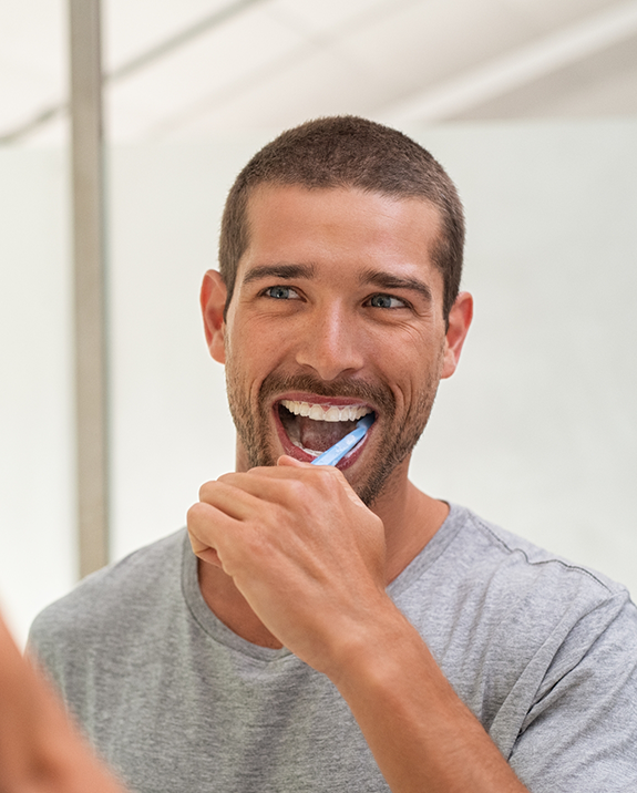 Man smiling while he brushes his teeth