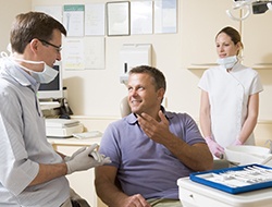Smiling man in dental chair talking to dentist