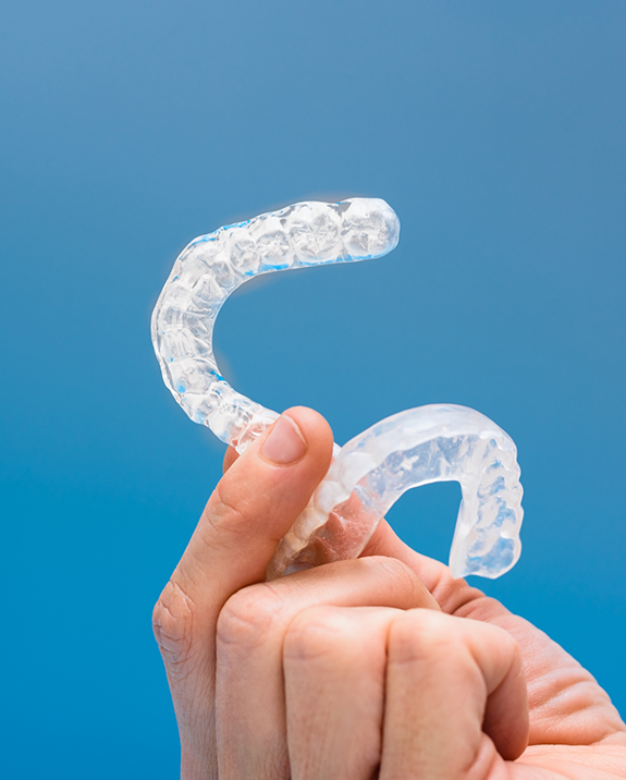 Hand holding two clear nightguard trays