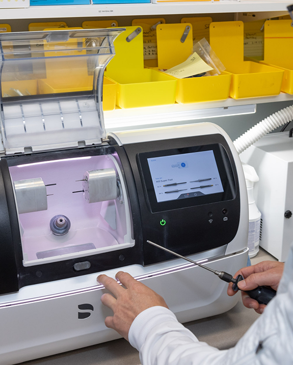Dentist adjusting a machine for CEREC same day dental crowns on a countertop