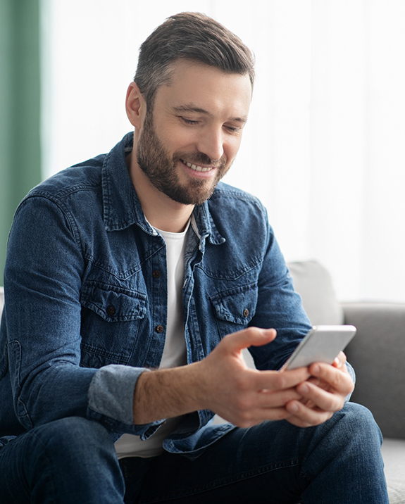 Man smiling while looking at his phone