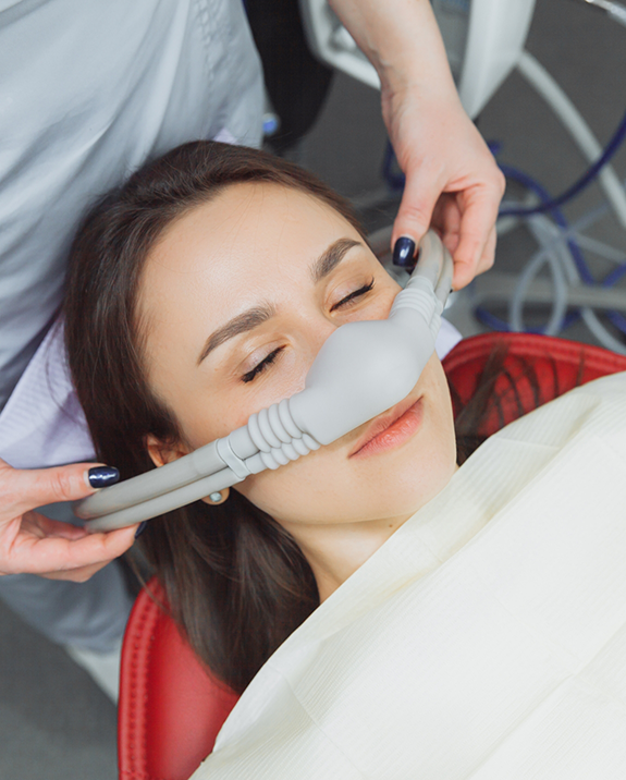 Relaxed woman in the dental chair with a mask over her nose for nitrous oxide sedation dentistry