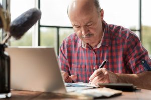 mature man writing on a notepad 