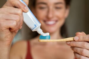 Woman putting toothpaste on toothbrush.