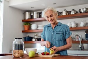 Woman cutting fruit to eat with her dentures