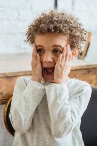 Young boy with hands on face